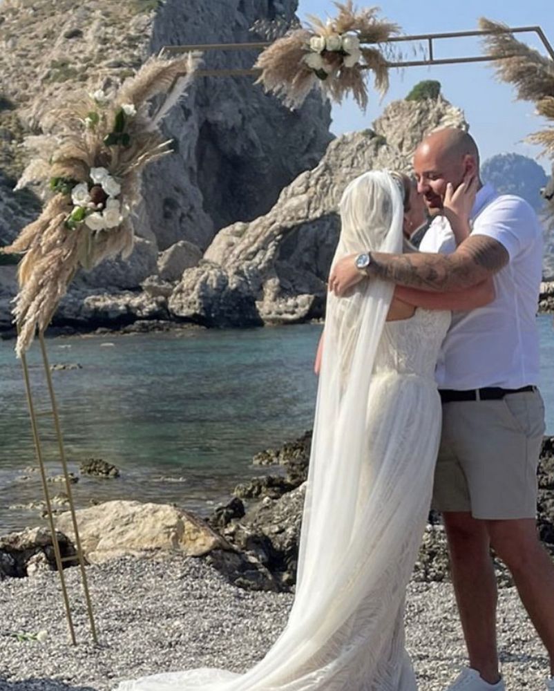 Bride and groom kissing under a beach arch